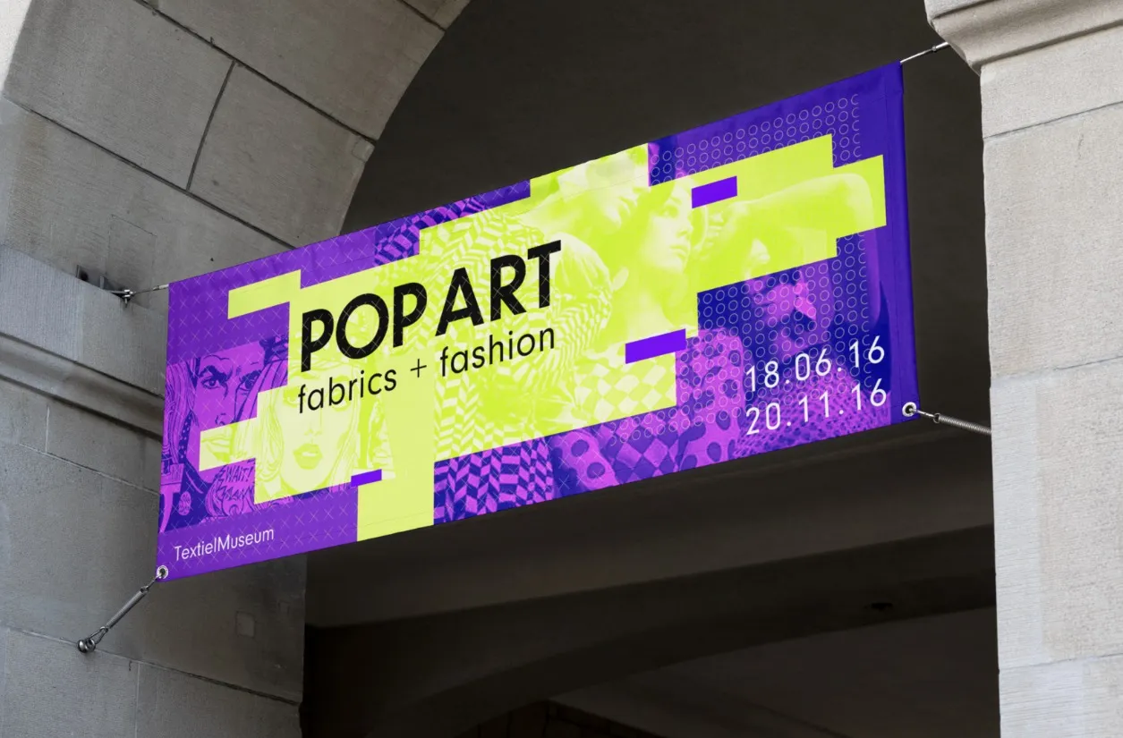 Photo-realistic mockup of a 'Pop Art fabrics + fashion' banner hung beneath a stone archway.