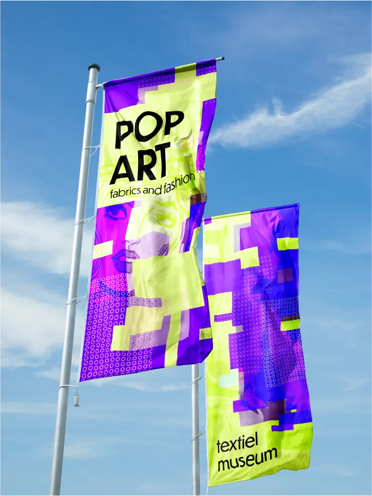Photo-realistic mockup of two 'Pop Art fabrics and fashion / textiel museum' flags against a blue sky.